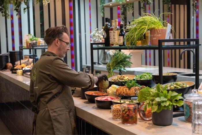 Cateringmedewerker die saladebar klaarzet in bedrijfsrestaurant